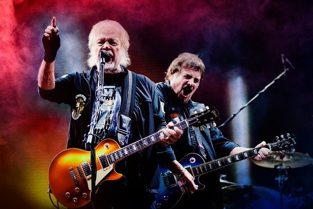 Two women playing drums in front of a temple